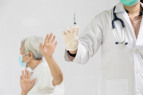 Hands of doctor preparing a syringe to inject the elderly, old people showing distrustful of COVID-19 vaccine, rejecting medicine, refusing to receive a Coronavirus vaccine injection